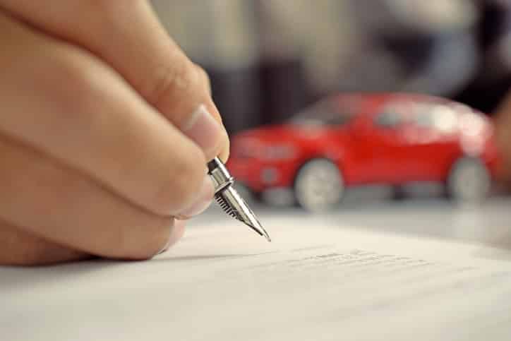 Man signing car insurance document. Writing signature on contract or agreement. Buying or selling new or used vehicle.